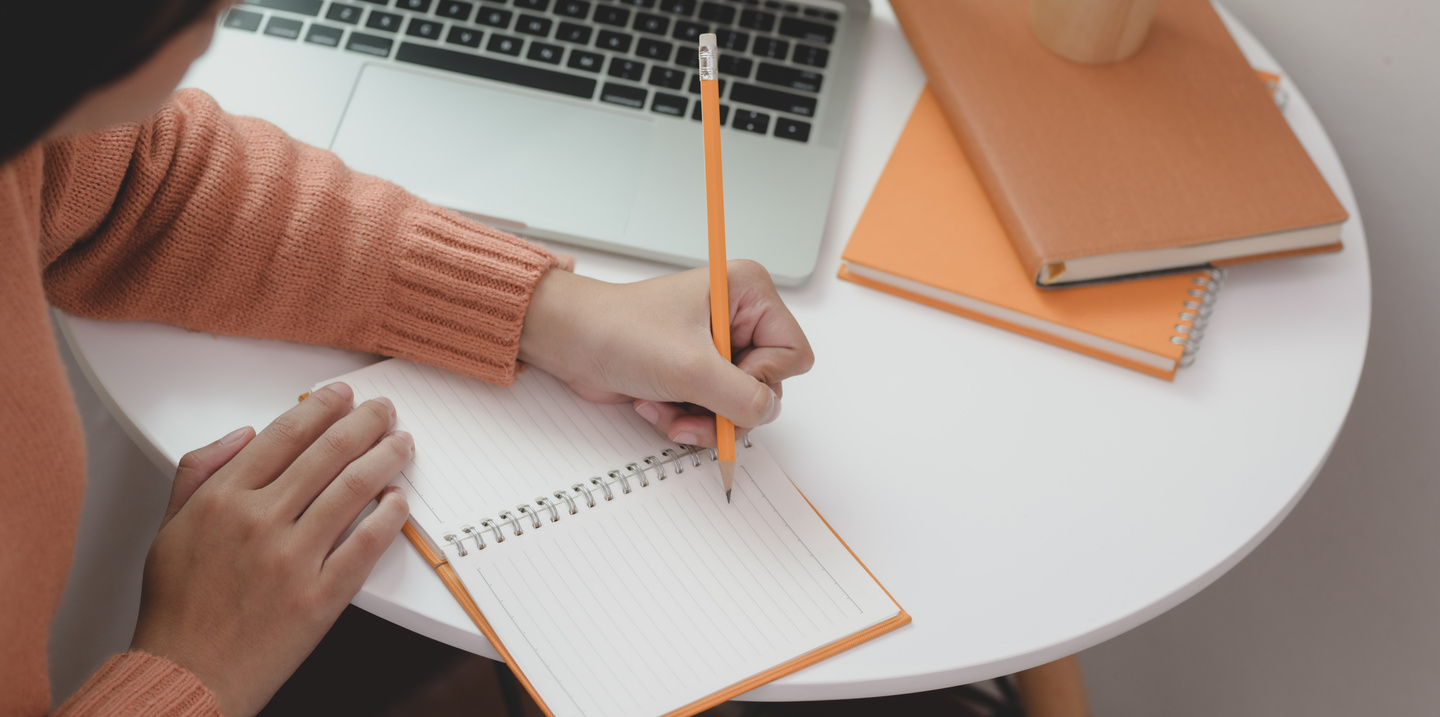 Crop female freelancer writing in notebook